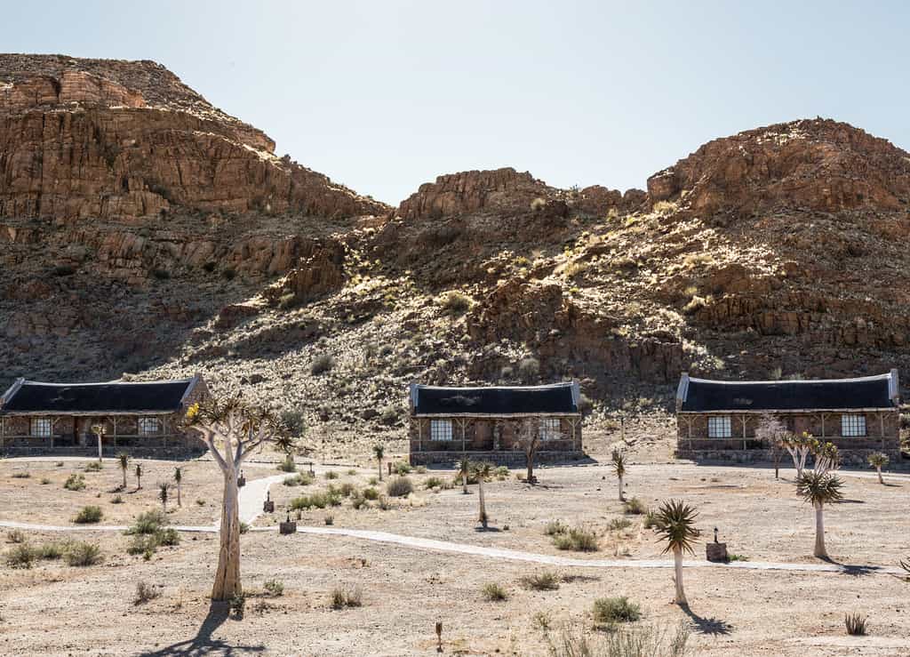 The bungalows lie at the foot of a sweeping rock face.