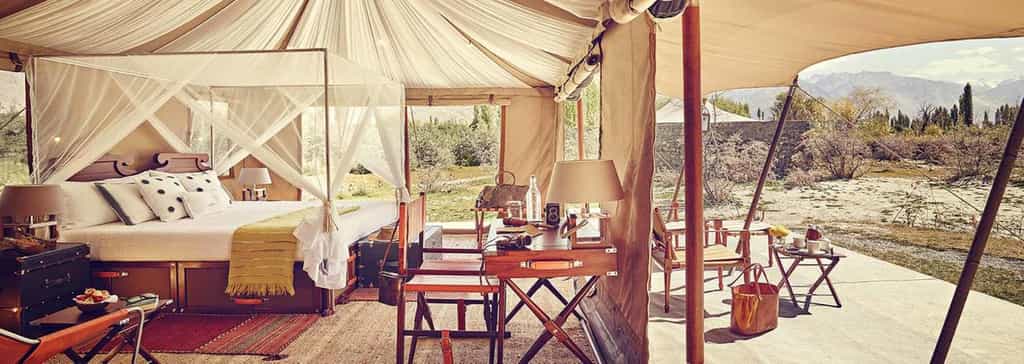 Private patio attached to each tent, furnished with hand-picked contemporary items with a nomadic theme, Intricately designed wooden chandeliers, Modern amenities like air-conditioners and heaters, Comfortable memory foam mattress that moulds perfectly to give you a good night’s sleep, The most luxurious fabrics, and a great selection of soft duvets and pillows, A writing desk, with custom stationery, A mini-bar and a complimentary welcome hamper, En-suite bathroom, A large cupboard, with an electronic safe, Shower cubicle with round-the-clock hot and cold water, Hair dryer and shaver socket, Custom-made bedroom slippers, eye masks and earplugs