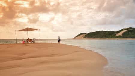 Couple on a romantic picnic on Inhaca Island are looking at the lodge.