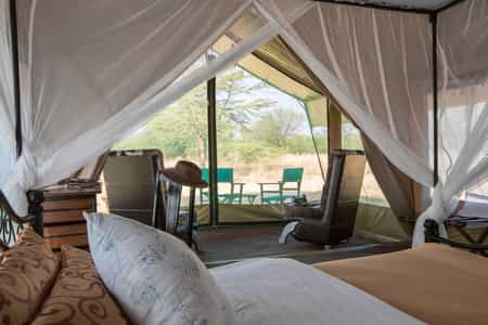 Netted porch and room with mosquito-netted beds, writing desk and private ensuite with bucket shower, flowing water to handbasin and flushing toilet